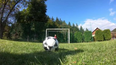 Küçük çocuklar futbol oynuyor. Çocuk kaleciye ateş eder ve kaleye sevinir..
