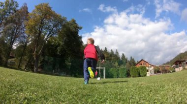 Küçük çocuklar futbol oynuyor. Çocuk kaleciye ateş eder ve kaleye sevinir..