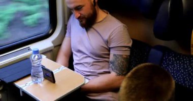 Trenle seyahat eden genç bir adam. Genç bir adam elektronik bir kitap okuyup tablet üzerinde çalışıyor..