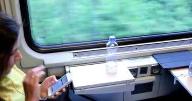 Genç bir kadın kardeşinle birlikte trenle seyahat ediyor. Genç bir kadın elektronik bir kitap okuyup tablet üzerinde çalışıyor..