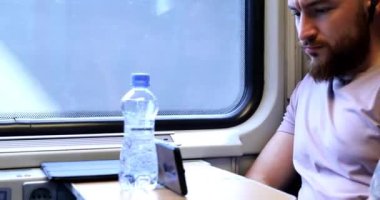 Trenle seyahat eden genç bir adam. Genç bir adam elektronik bir kitap okuyup tablet üzerinde çalışıyor..
