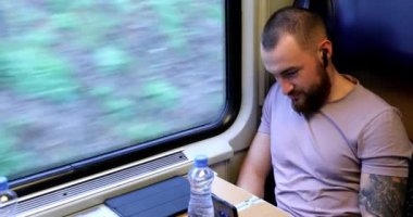 Trenle seyahat eden genç bir adam. Genç bir adam elektronik bir kitap okuyup tablet üzerinde çalışıyor..