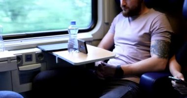 Trenle seyahat eden genç bir adam. Genç bir adam elektronik bir kitap okuyup tablet üzerinde çalışıyor..