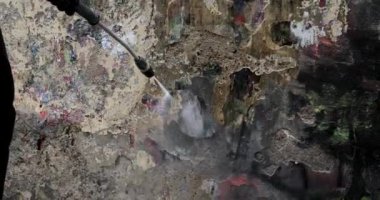 Boyalı bir duvardan duvar yazısını silmek. İşçi boyalı duvarı spreylerden temizler..