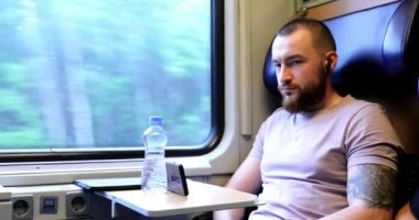 Trenle seyahat eden genç bir adam. Genç bir adam elektronik bir kitap okuyup tablet üzerinde çalışıyor..