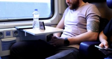 Trenle seyahat eden genç bir adam. Genç bir adam elektronik bir kitap okuyup tablet üzerinde çalışıyor..