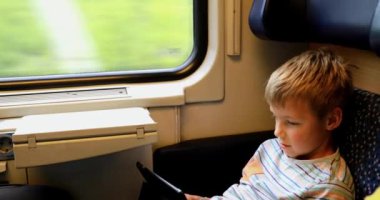 Trenle seyahat eden genç bir adam. Genç bir adam elektronik bir kitap okuyup tablet üzerinde çalışıyor..