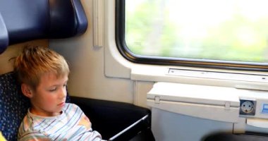 Trenle seyahat eden genç bir adam. Genç bir adam elektronik bir kitap okuyup tablet üzerinde çalışıyor..