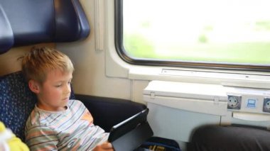 Trenle seyahat eden genç bir adam. Genç bir adam elektronik bir kitap okuyup tablet üzerinde çalışıyor..