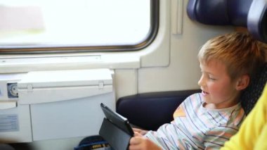 Trenle seyahat eden genç bir adam. Genç bir adam elektronik bir kitap okuyup tablet üzerinde çalışıyor..
