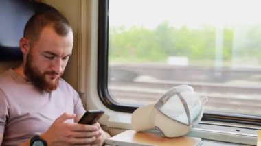 Trenle seyahat eden genç bir adam. Genç bir adam elektronik bir kitap okuyup tablet üzerinde çalışıyor..