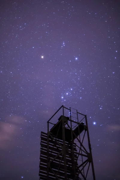 Uma torre com um céu estrelado em um fundo — Fotografia de Stock