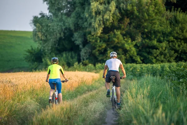 Hombre y mujer montando bicicletas en el campo — Foto de Stock