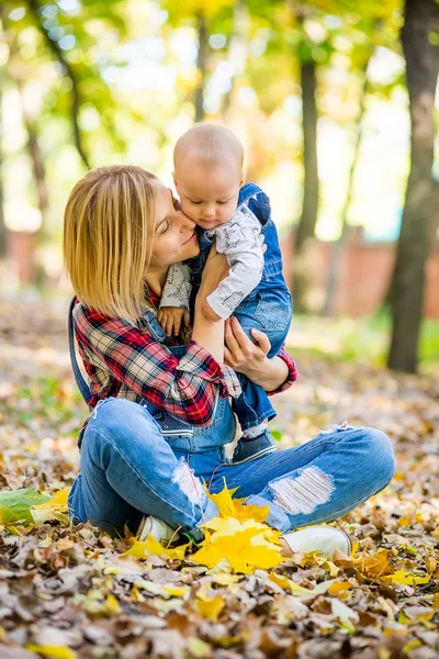 Junge Mutter spielt im Herbst mit Baby im Park — Stockfoto