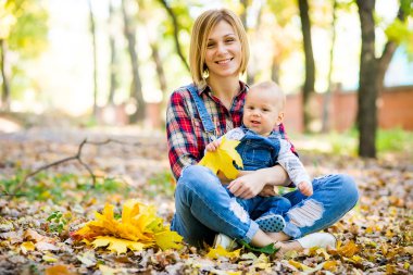 genç anne bebek Park ile sonbaharda oynarken