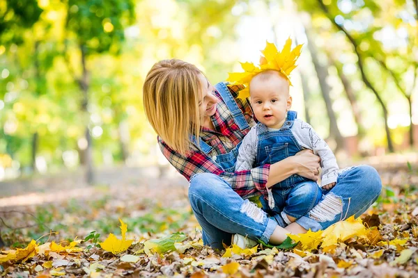 Junge Mutter spielt im Herbst mit Baby im Park — Stockfoto