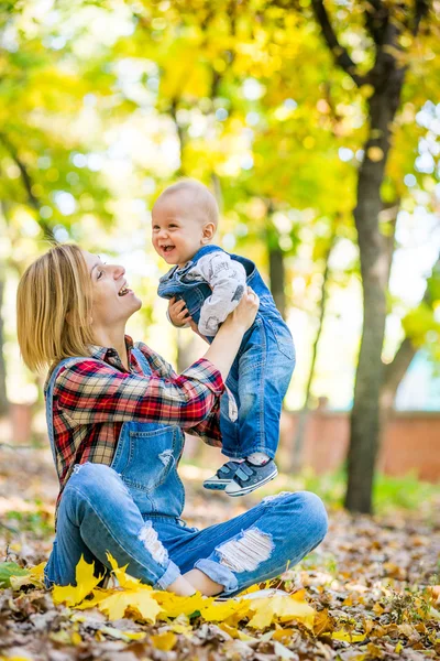 Junge Mutter spielt im Herbst mit Baby im Park — Stockfoto