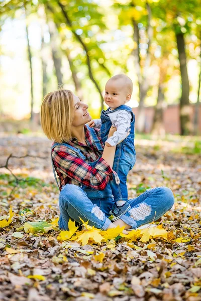 Junge Mutter spielt im Herbst mit Baby im Park — Stockfoto