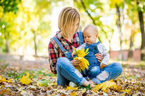 Junge Mutter spielt im Herbst mit Baby im Park — Stockfoto