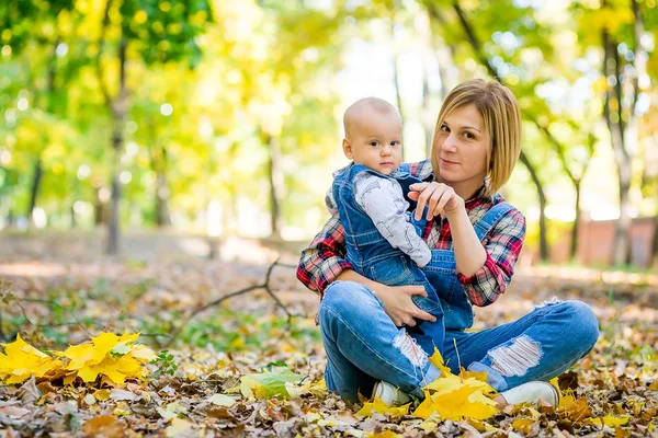 Jovem mãe brincando com bebê no parque no outono — Fotografia de Stock