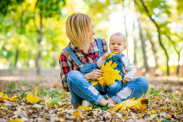 Jonge moeder spelen met de baby in het park in het najaar — Stockfoto