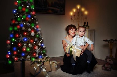 Bir bebek evde şömine yakın Noel ağacı oturma ile mutlu anne .