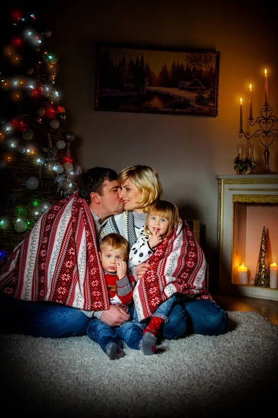 Ευτυχισμένη οικογένεια κάθεται κοντά ένα χριστουγεννιάτικο δέντρο το βράδυ εν όψει των Χριστουγέννων — Φωτογραφία Αρχείου