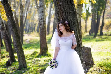 Sonbaharda bir ağacın yanında duran güzel gelin.