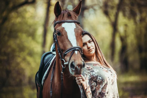 Ung flicka med en häst i skogen. — Stockfoto