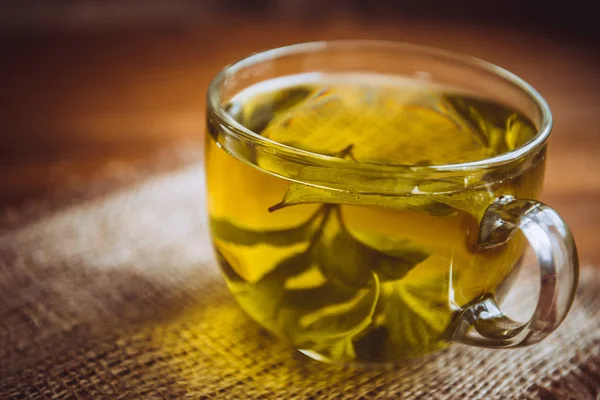 Xícara de chá de ervas fica em uma mesa de madeira marrom — Fotografia de Stock