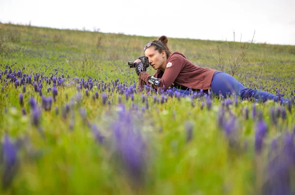 Menina fotografando flores em um prado — Fotografia de Stock