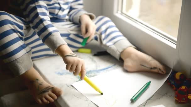 小さな男の子は、ウィンドウで、マーカーを描画します窓辺 — ストック動画
