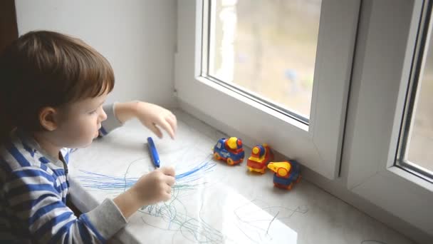 Kleine jongen trekt een marker op het venster, vensterbank — Stockvideo