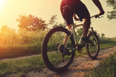 Adam parkta bisiklet sürüyor.