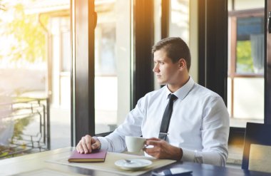 Bir kitap ile bir kafede oturan genç adam