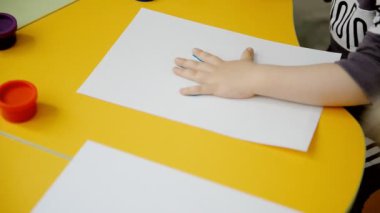 Çocuk elini boya ile boyar.