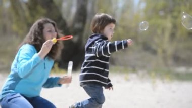 Sabun köpüğü kumsalda oynarken anne çocuk