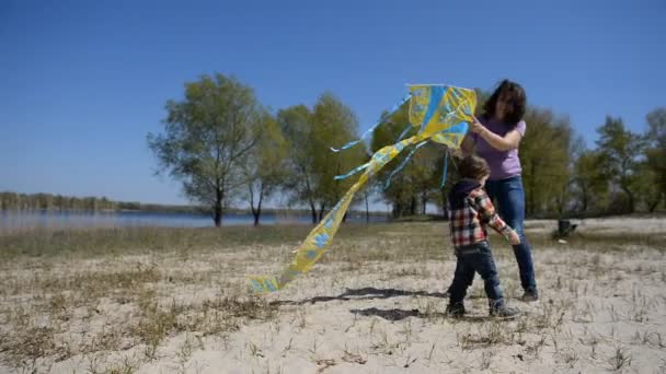 Bébé avec maman jouant au cerf-volant sur la plage . — Video