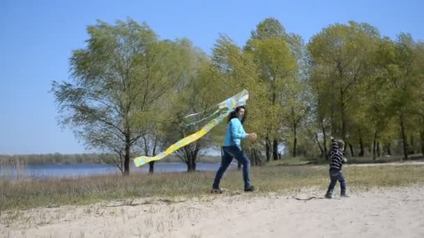 Bébé avec maman jouant au cerf-volant sur la plage . — Video