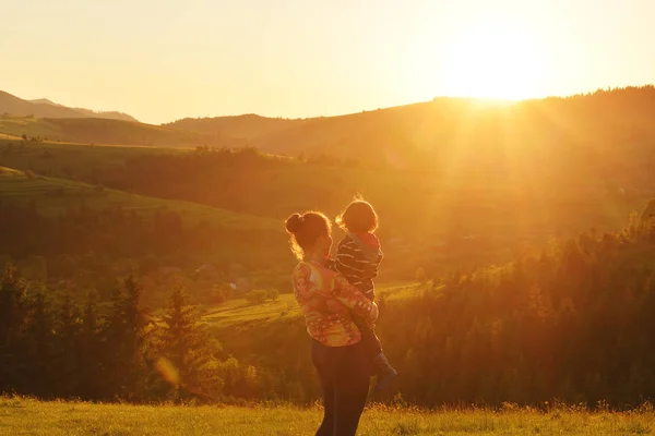 Μαμά και το μωρό να σταθεί και να παρακολουθήσετε το ηλιοβασίλεμα στα βουνά — Φωτογραφία Αρχείου