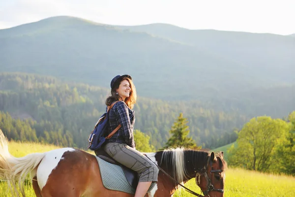 A woman is sitting on a horse in the mountains