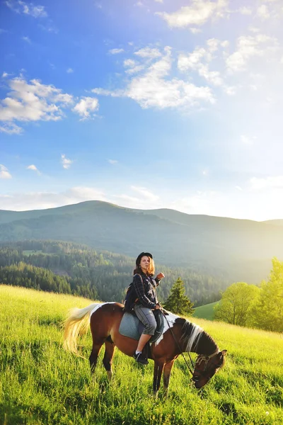 Una donna è seduta su un cavallo in montagna — Foto Stock