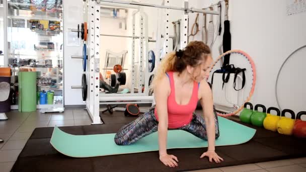 Beautiful young woman is engaged in gymnastics in the gym. — Stock Video