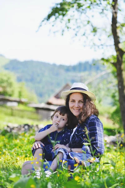 Eine Frau mit Baby sitzt im Gras in den Bergen. — Stockfoto
