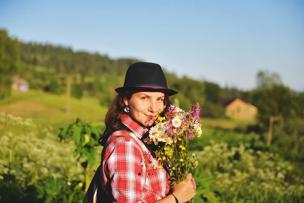 Ragazza che tiene un mazzo di fiori selvatici per una passeggiata in montagna — Foto Stock