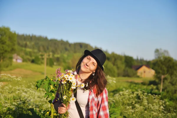 Ragazza che tiene un mazzo di fiori selvatici per una passeggiata in montagna — Foto Stock