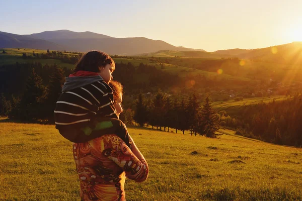 Μαμά και το μωρό να σταθεί και να παρακολουθήσετε το ηλιοβασίλεμα στα βουνά — Φωτογραφία Αρχείου