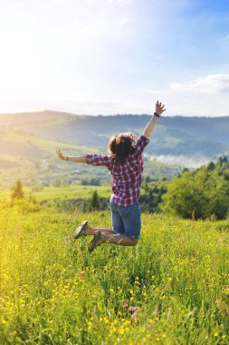 Yaz aylarında dağların bir çayır üzerinde sevinç için atlama kadın
