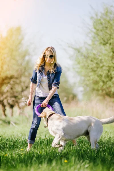 Sarışın bir labrador ile oynuyor.