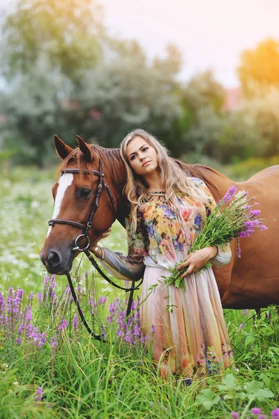 Młoda kobieta stoi w pobliżu konia w letnią sukienkę na łące — Zdjęcie stockowe